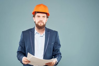 Erkek mühendis belgeleri elinde ve koruyucu üniforma çiziyor.