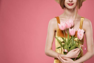 Bir kadının elinde pembe bir buket çiçek vardı. Altın bir elbise, lüks bir süs.