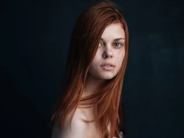 Mulher com ombros nus e maquiagem cabelo vermelho fundo escuro — Fotografia de Stock