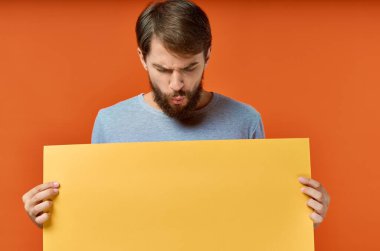 Sarı pankart taşıyan komik adam turuncu arka plan