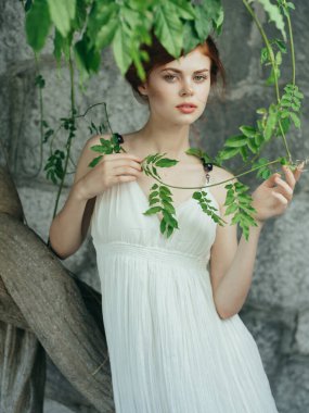 Yunanistan 'ın ağaç tabanlı taş duvarının yanındaki beyaz elbiseli kadın.