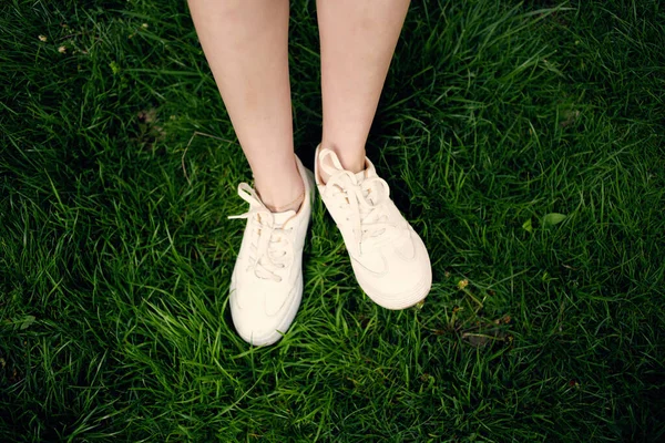 Frauenfüße auf dem Rasenspaziergang im Park — Stockfoto