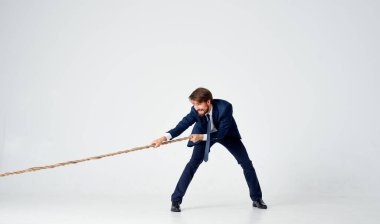 Takım elbiseli bir adam halat çekme kariyeri ışık arka planı