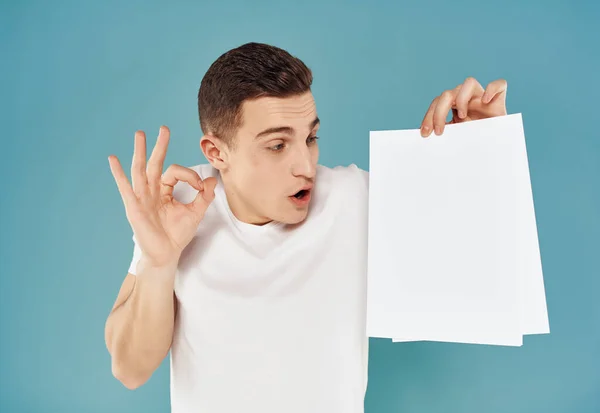 Knappe man in een wit t-shirt een vel papier in zijn handen Kopieer Space close-up — Stockfoto