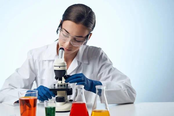 Assistente de laboratório em um microscópio de mesa de trabalho casaco branco diagnósticos biotecnologia — Fotografia de Stock