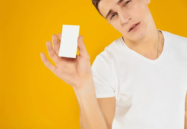 Mężczyzna w białym t-shirt business card manager skopiować przestrzeń żółty tło — Zdjęcie stockowe