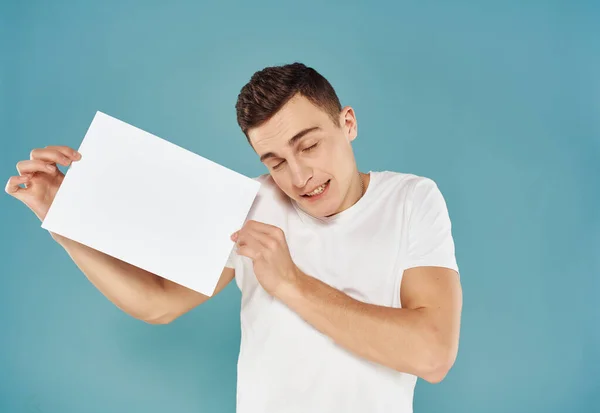 man in white t-shirt with white sheet of paper in his hands Copy space