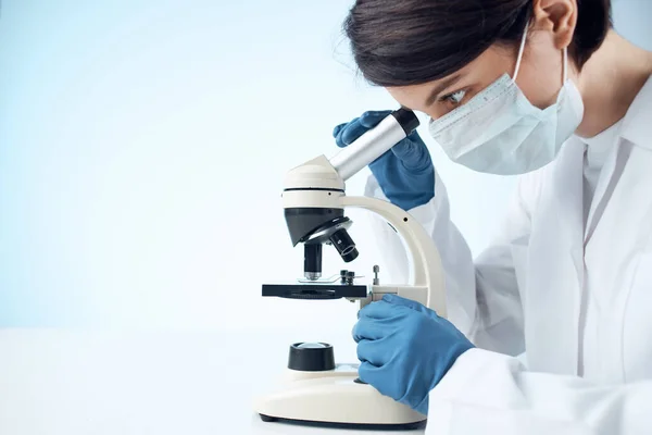 laboratory assistant in medical mask microscope analysis research