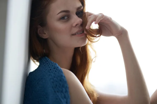 Mooie vrouw zittend op de vensterbank met een blauwe ruit — Stockfoto