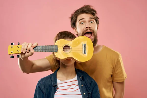 Neşeli genç çift ukulele pembe arka plan eğlenceli moda — Stok fotoğraf