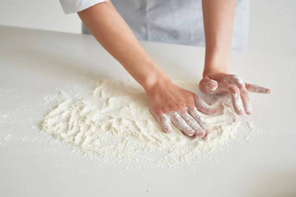woman baker rolls out dough working with flour