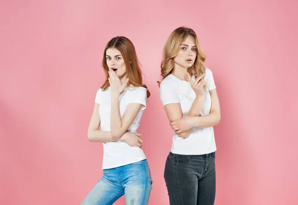 Dos mujeres en camisetas blancas moderno verano estilo amistad emociones rosa fondo —  Fotos de Stock