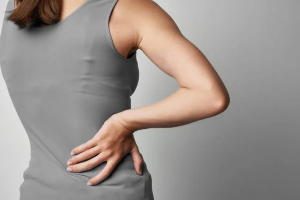 Mujer en gris camiseta sosteniendo su espalda salud problema reumatismo medicina —  Fotos de Stock