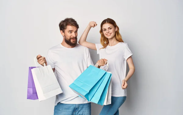 Молодая пара в белых футболках пакеты образ жизни покупки продажи — стоковое фото