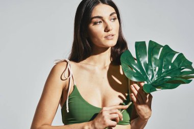 Plajdaki bikinili kadın palmiye yaprağı gibi poz veriyor.