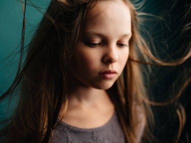 Kapalı yeşil arka plan pozu veren dalgalı saçlı bir kız.