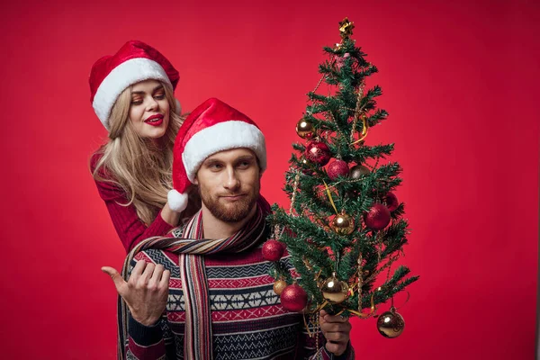 Jovem casal Natal árvore brinquedos feriado alegria vermelho fundo — Fotografia de Stock
