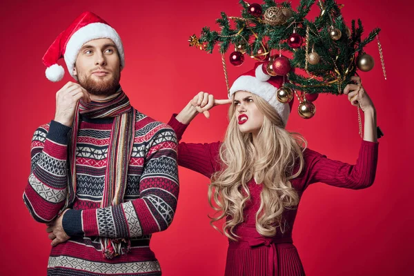 Fröhlich junges Paar Weihnachtsbaum Spielzeug Urlaub roter Hintergrund — Stockfoto