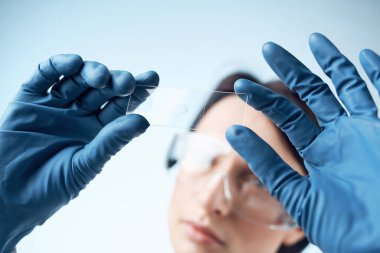 Mavi eldivenli kadın araştırma analizlerini test ediyor.