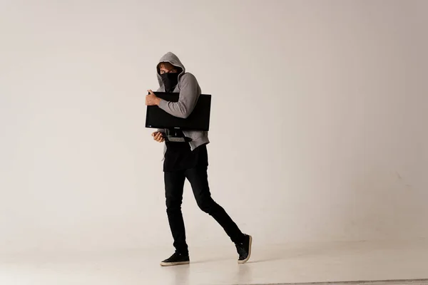 Een man met een monitor in zijn handen steelt een computer anonimiteit Hacker Studio — Stockfoto