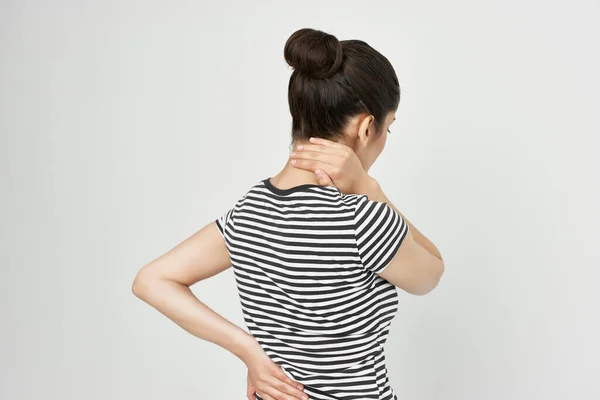 Bruneta v pruhovaném tričku bolest v krku světlo na pozadí — Stock fotografie