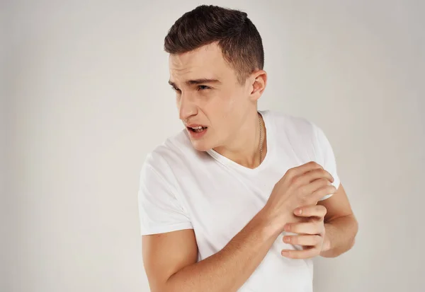 Hombre en blanco camiseta emociones irritabilidad luz fondo —  Fotos de Stock