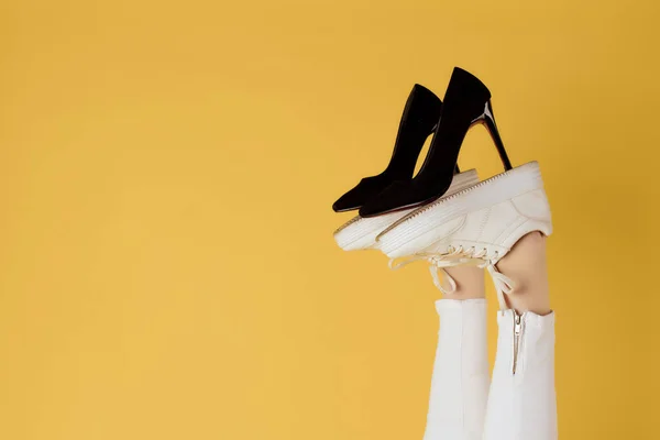 Mulheres sapatos pretos em pernas invertidas fundo amarelo — Fotografia de Stock