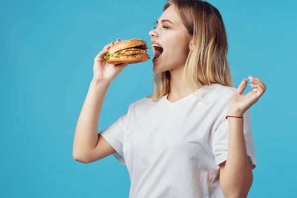 Blond in wit t-shirt hamburger fast food snack vreugde — Stockfoto