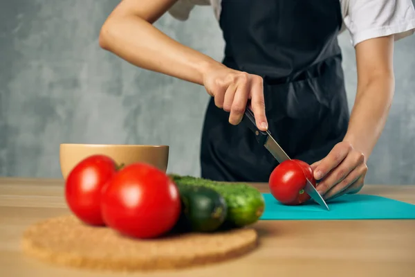 Femme dans un tablier noir dans la cuisine coupe légumes cuisine salade vitamines — Photo