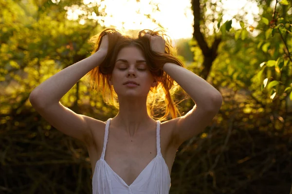 Atractiva mujer en un vestido blanco sosteniendo su cabello al aire libre verano — Foto de Stock