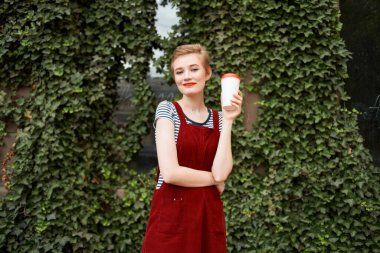 Elinde bir fincan kahveyle gezen güzel bir kadın.