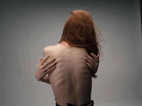 Vrouw met rood haar staat rug ribben figuur — Stockfoto