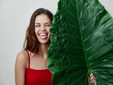 Dil çıkaran neşeli kadın. Kırmızı mayo palmiye yaprağı stüdyosu.