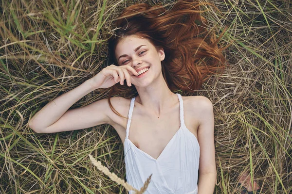 Mujer alegre en el campo se encuentra en la hierba sonreír vacaciones verano —  Fotos de Stock