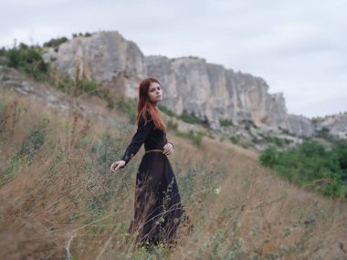 Siyah elbiseli kadın dağ yürüyüşü yapıyor.