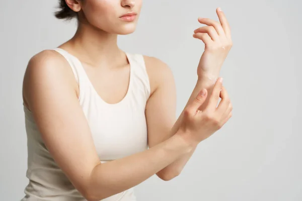 Mujer en camiseta blanca aplicar crema en sus manos cuidado de la piel fondo claro — Foto de Stock
