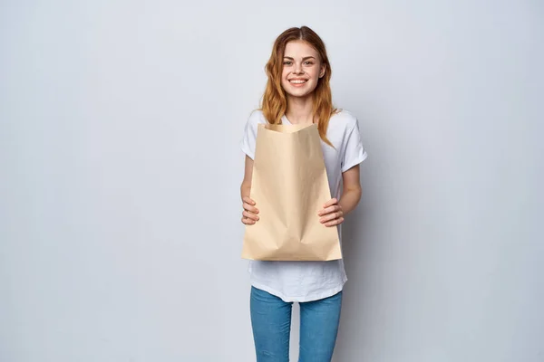 Cheerful woman in white t-shirt paper shopping bag — Stock Photo, Image