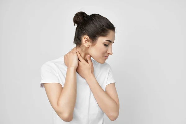Morena em um branco t-shirt dor no pescoço luz fundo — Fotografia de Stock