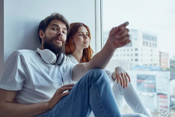 Hombre y mujer se sientan cerca de la ventana con auriculares romance alegría — Foto de Stock