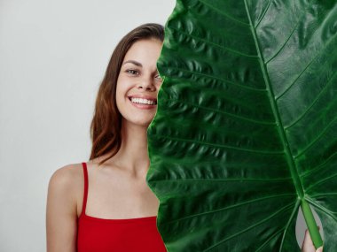 Kırmızı mayo giymiş güzel bir kadın. Palmiye yaprağı gülüşü. Egzotik.