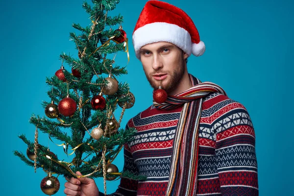 Noel Baba şapkalı yakışıklı adam Noel süsleri Noel stüdyosunda poz veriyor. — Stok fotoğraf