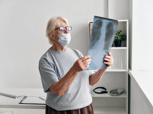 Starší žena s rentgenovými snímky v ordinaci lékaři covid-19 pas — Stock fotografie