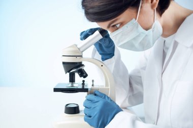 Kadın laboratuvar asistanı mikroskop araştırması yapıyor.