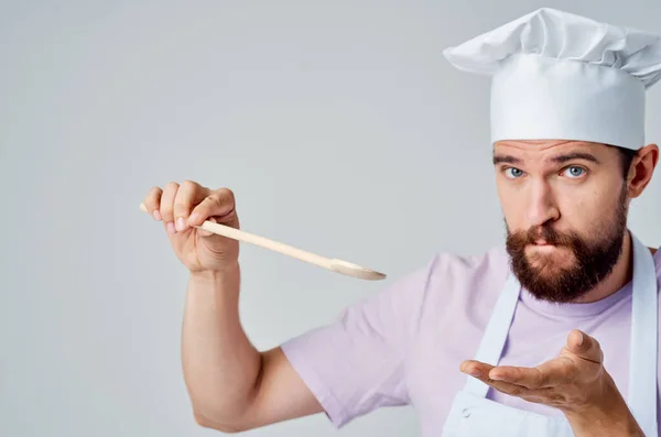 Chef com um boné branco na cabeça segurando uma colher em suas mãos cozinhar comida cozinha trabalho — Fotografia de Stock