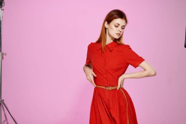 Kırmızı elbiseli güzel bir kadın. El hareketi. Pembe arka plan.