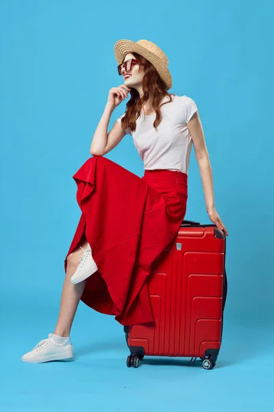 Женщина сидит на красный чемодан путешествия образ жизни полет синий фон — стоковое фото