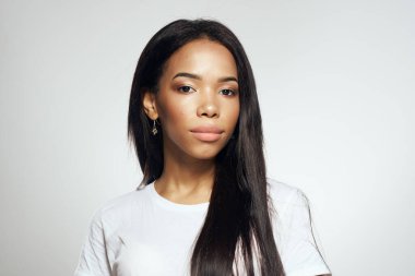 Beyaz tişörtlü, uzun saçlı, küpeli güzel bir kadın.