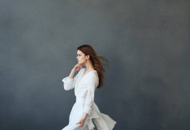 Beyaz elbise stüdyosunda dans eden güzel bir kadın.