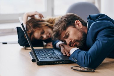 İşadamı ve kadın laptopun önünde büroda çalışıyor.