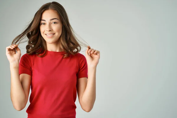 Bonita mulher em um branco t-shirt cabelo cuidado luz fundo — Fotografia de Stock